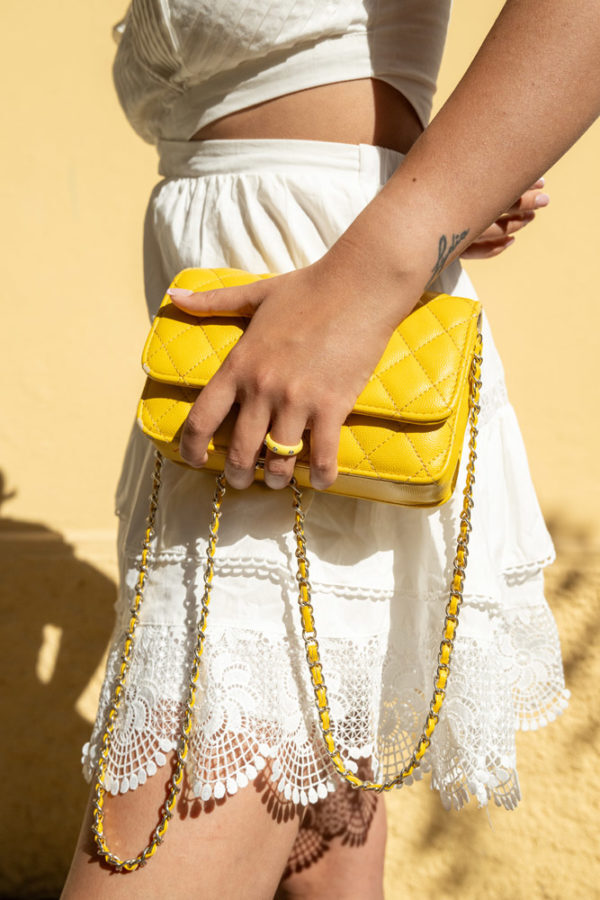 Main portant une bague My First Diamond sur un sac jaune